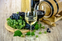 two glasses of wine and grapes on a wooden table